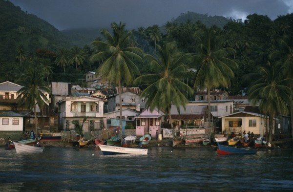 ST LUCIA, Soufriere, "Coastal housing and palm trees with colourful boats pulled up along shore.