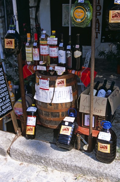 BULGARIA, Melnik., "Display of wine bottles, barrel, and containers outside shop."