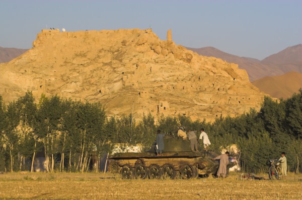 AFGHANISTAN, Bamiyan Province, Bamiyan, "Children playing on abandoned tanks in fied in front of