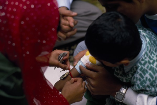 ENGLAND, Religion, Woman tying thread on arm of boy during the Sacred Thread ceremony. The Hindu