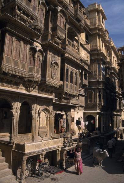 INDIA, Rajasthan, Jaisalmer, Patwon ki Haveli exterior with people and cattle seen on the path at