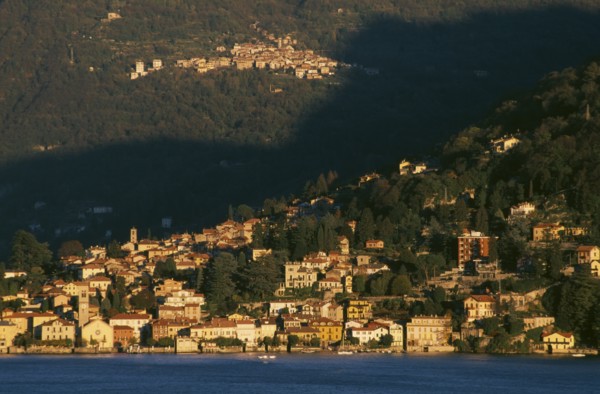 ITALY, Lombardy, Lake Como, Torno.  View across Lake Como towards town spread across hillside in