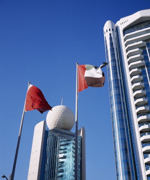 UAE, Dubai, Deira, Etisalat Building on Dubai Creek with flag poles in foreground.