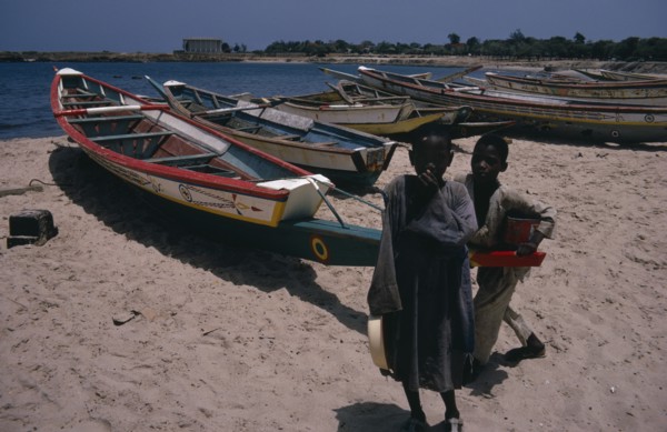 SENEGAL, Fishing, Two children on beach beside line of painted fishing boats pulled up onto the