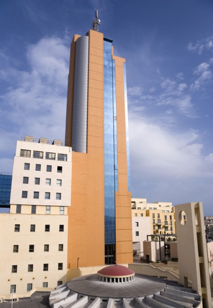 MALTA, Saint Julians, Portomaso Hilton Tower office complex towering above a small church with dome