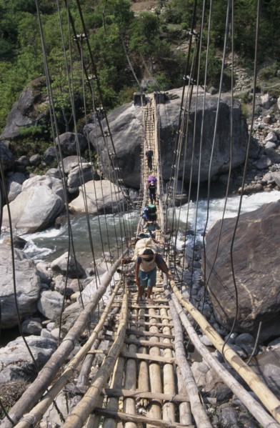 NEPAL, Annapurna Circuit Trek, Crossing a sagging suspension bridge over the Khudi Khola at Khudi.