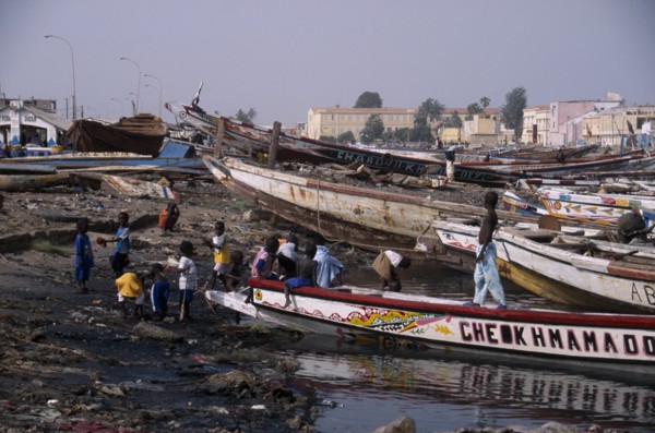 SENEGAL, St Louis, Children playing on shore next to beached boats.