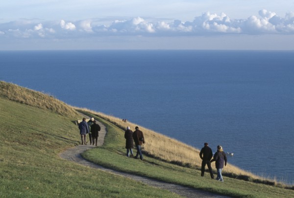 ENGLAND, East Sussex, Eastbourne, People walking together along winding path on cliff walk by