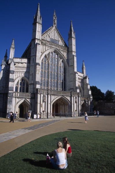 ENGLAND, Hampshire, Winchester, Winchester Cathedral exterior seen from the gardens with two girls