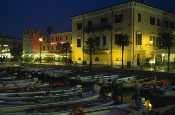 ITALY, Veneto, Lake Garda, Bardolino.  Harbour and moored boats at night with waterside bars and