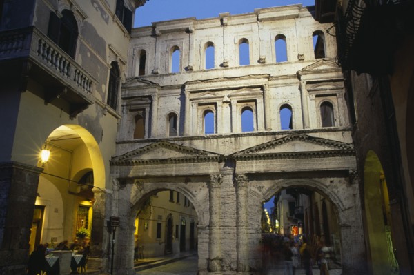ITALY, Veneto, Verona, Street scene and Roman gateway at night with group of people framed in