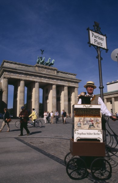 GERMANY, Berlin, Brandenburg Gate. Man in foreground under Pariser Platz sign performing with a