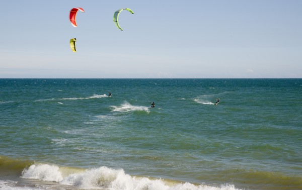 ENGLAND, West Sussex, Lancing, Kite Surfers on sea next to beach in the summer with blue sky