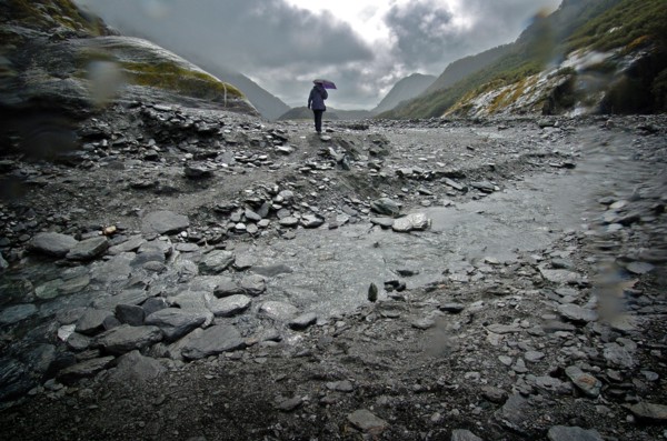NEW ZEALAND, SOUTH ISLAND, WEST COAST, "MOUNT COOK NATIONAL PARK, A WALKER CROSSES A STREAM INFRONT