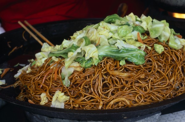 CHINA, Beijing, Donghua Yeshi food market.  Noodles and pak choi in wok.