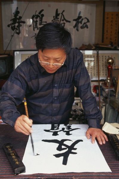 CHINA, Beijing, Caligrapher at work in Hutong workshop.