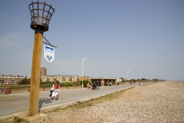 ENGLAND, West Sussex, Littlehampton, People walking along the promenade next to shingle beach with