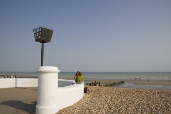 ENGLAND, West Sussex, Bognor Regis, Two young women sitting on a white wall facing each other