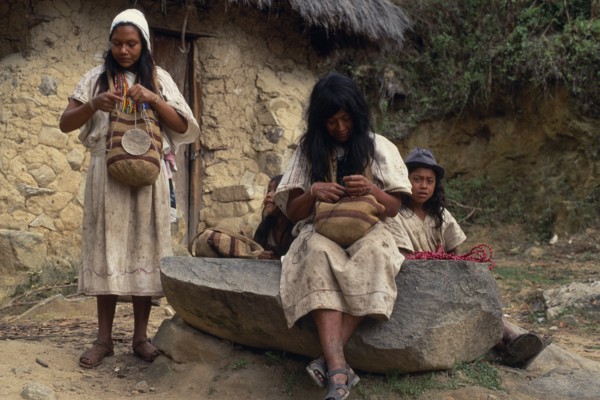COLOMBIA, Sierra Nevada de Santa Marta, Ika, Ika women outside mud wattle thatched home sewing