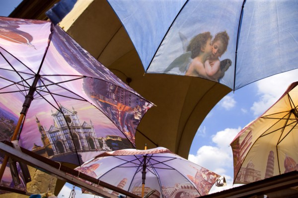 ITALY, Tuscany, Florence, Brightly coloured umbrellas for sale on the Ponte Vecchio with images of