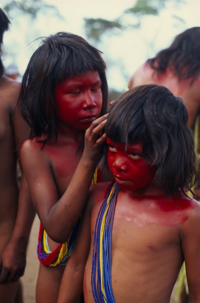 BRAZIL, Mato Grosso, Indigenous Park of the Xingu, Young Panara girls applying red karajuru face