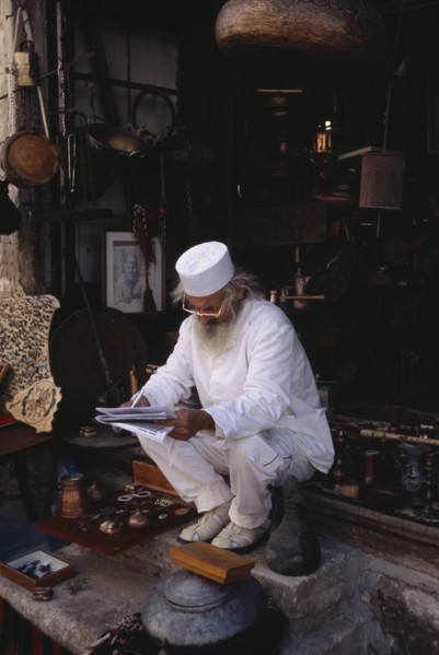 BOSNIA & HERZEGOVINA, Balkan Peninsula, Mostar, Elderly man wearing white sitting on step at