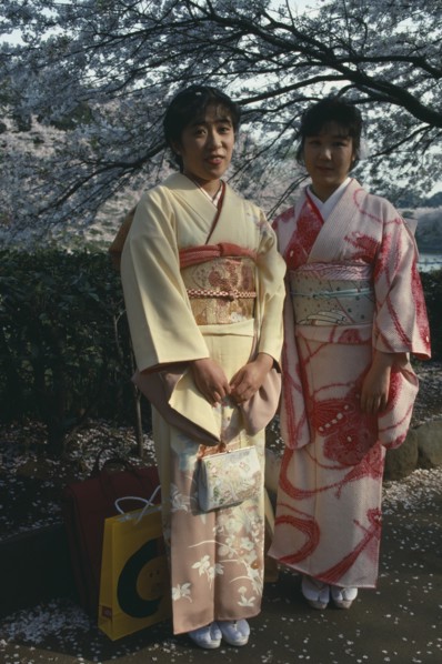JAPAN, Honshu, Tokyo, Two young women wearing traditional kimonos whilst stood under a cherry
