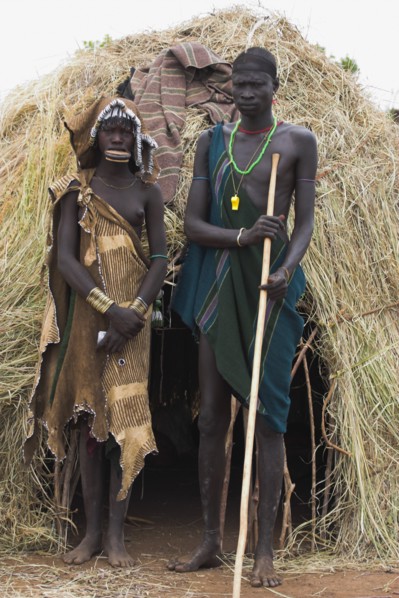 ETHIOPIA, South Omo Valley, Mursi Tribe, Couple standing outside their hut
