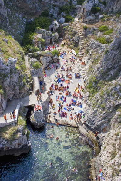 ITALY, Puglia, Lecce, Tricase.  Looking down on people sunbathing on coloured beach towels laid out