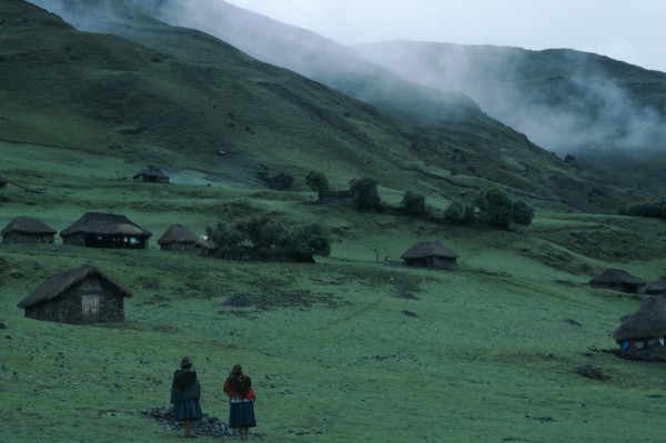 PERU, Ayacucho Province, Choquetira , Village of thatched homes on green hillside with mist seen
