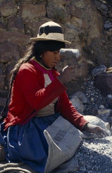 BOLIVIA, Chukiuta, Woman knelling on a Banco Minero de Bolivia sack breaking rocks into small