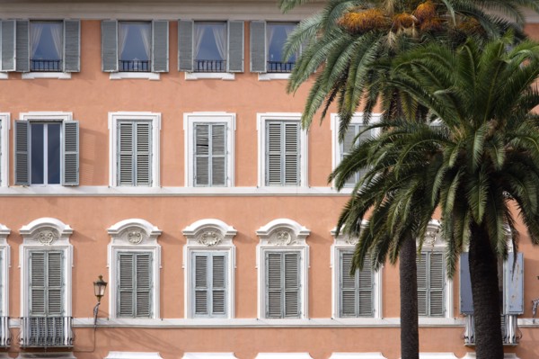 ITALY, Lazio, Rome, Palm trees in front of a pink building with pale blue shuttered windows in