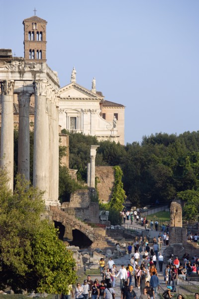 ITALY, Lazio, Rome, Tourists walking past the Temple of Antoninus and Faustina in the Forum with