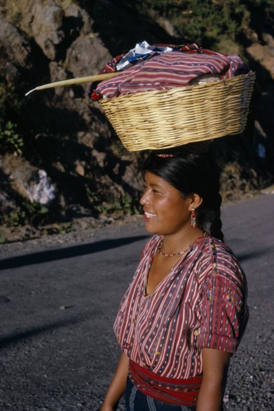 GUATEMALA, Lake Atitlan, Indian girl walking along road carrying a basket of washing on top of her