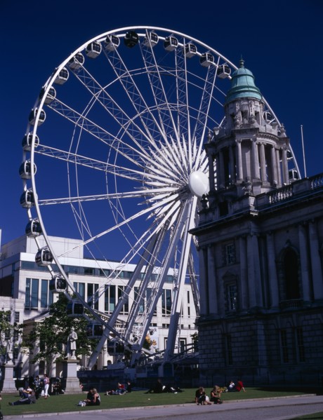 IRELAND, North, Belfast, People sitting or lying in the sun in the grounds of City Hall with The