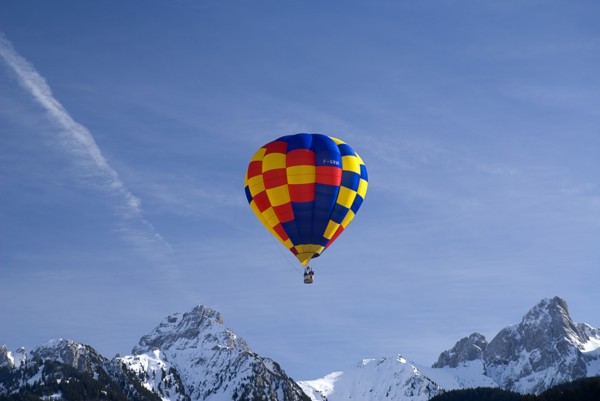 SWITZERLAND, Canton de Vaud, Chateau d'Oex, One Hot Air Balloon in flight above jagged snow covered