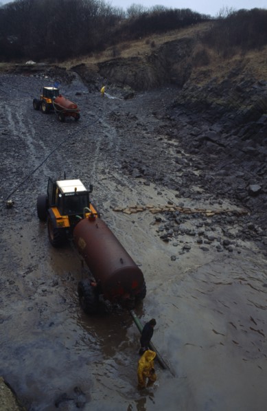 Wales, Dyfed, Stackpole Quay, Workers clearing beached oil from grounded tanker the Sea Empress in