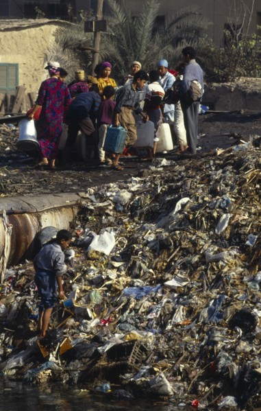 Egypt, Cairo, People standing beside rubbish tip in the Imbaba area of the city.