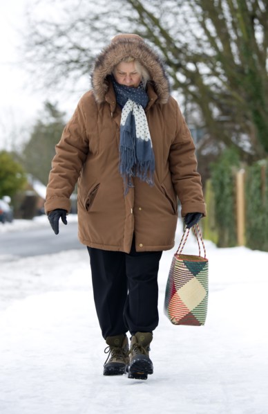 England, West Sussex, Chichester, Middles aged woman in warm clothing carrying shopping bag and