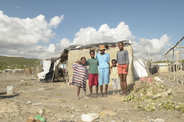 HAITI, Isla de la Laganave, family stood outside their shack in slum area.