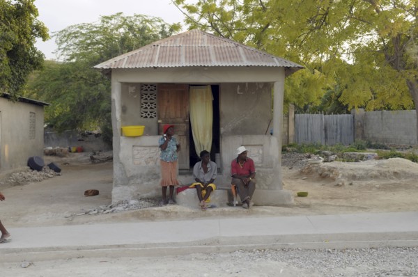 Haiti, Isla de Laganave, local people sat outside hime with tin roof.