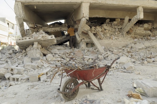 Haiti, Isla de Laganave, Building damaged by earthquake, man salvaging iron reinforcing rods from