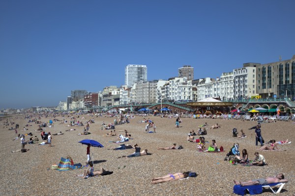 England, East Sussex, Brighton, people sunbathing on the pebble beach.