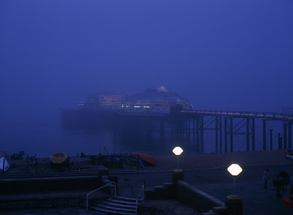 Brighton, East Sussex, England. The West Pier illuminated in evening light with mist on the sea