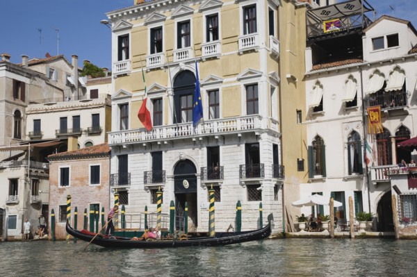 Venice, Veneto, Italy. Gondolier steers gondola from Rialto bridge along Grand Canal with Venice