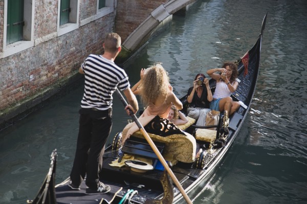 Venice, Veneto, Italy. Centro Storico Gondolier steering gondola along canal as models are