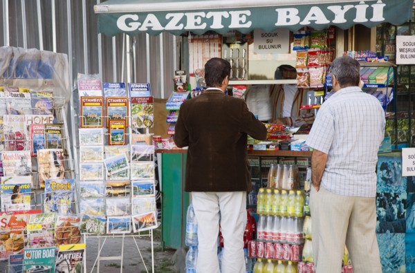Istanbul, Turkey. Sultanahmet. Customers at newspaper kiosk with magazine stand and display of maps