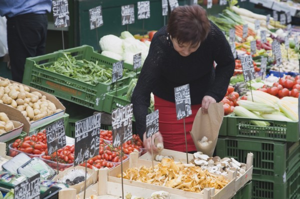 Vienna, Austria. The Naschmarkt. Stallholder selecting mushrooms from display of fresh produce also