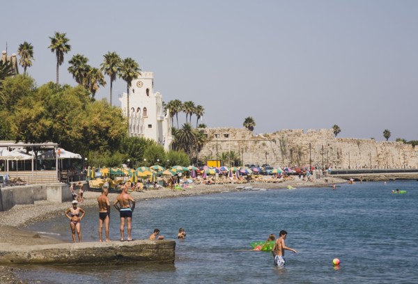 Kos, Dodecanese Islands, Greece. Kos Town beach with castle walls and harbour entrance behind and