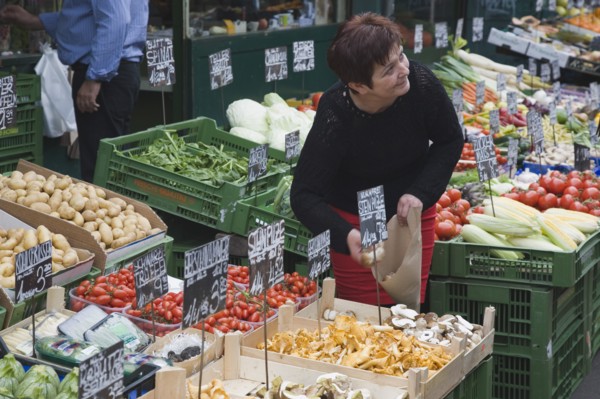 Vienna, Austria. The Naschmarkt. Stallholder selecting mushrooms from display of fresh produce also